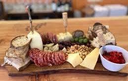 A charcuterie board with meats, cheeses, fruit, and bread
